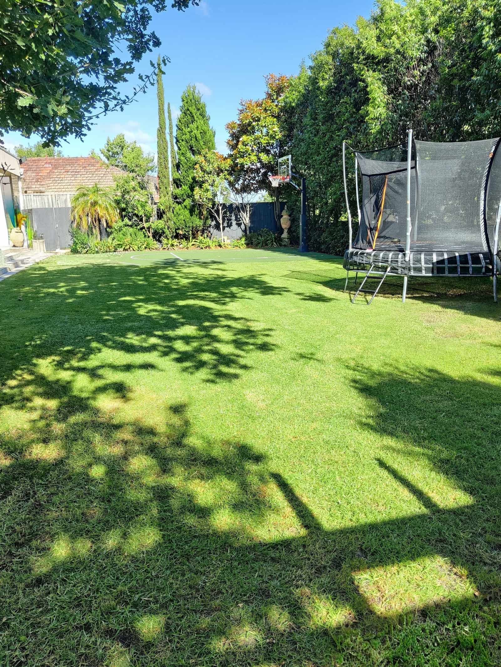 Lawn with basketball court and trampoline